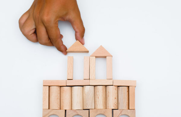 Business strategy concept on white background flat lay. man building castle from wooden blocks.
